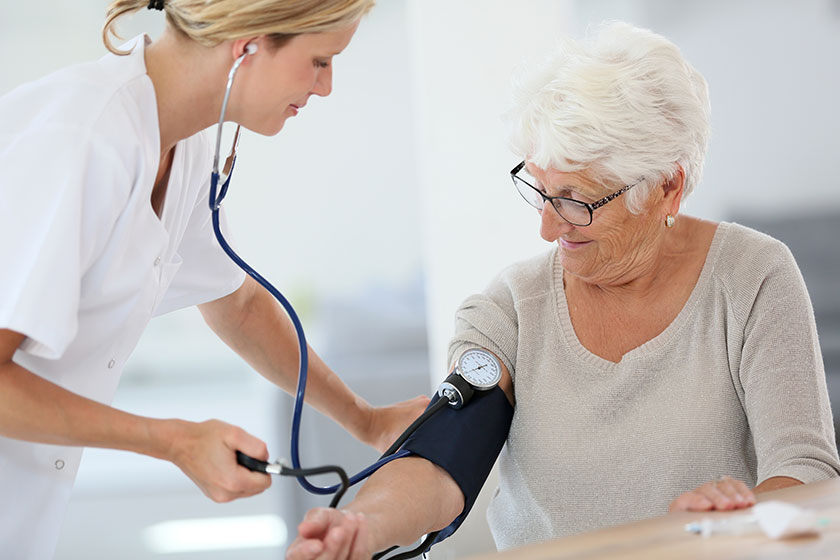 doctor checking elderly woman blood pressure