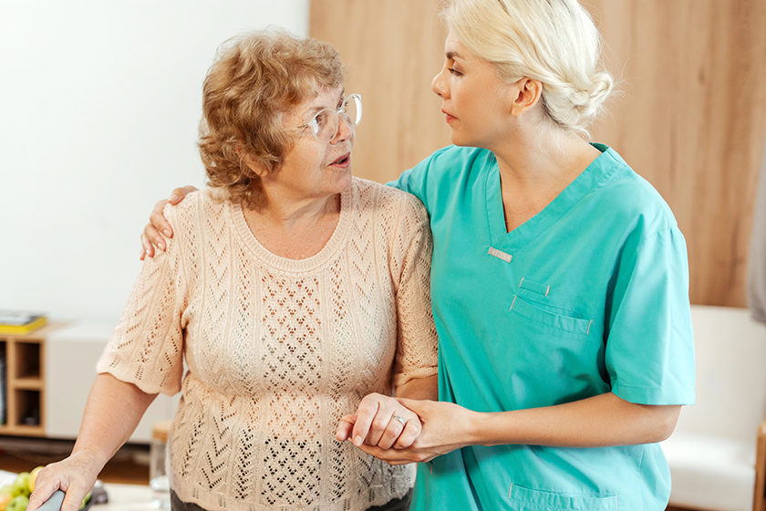 nurse supporting elderly woman using walking frame