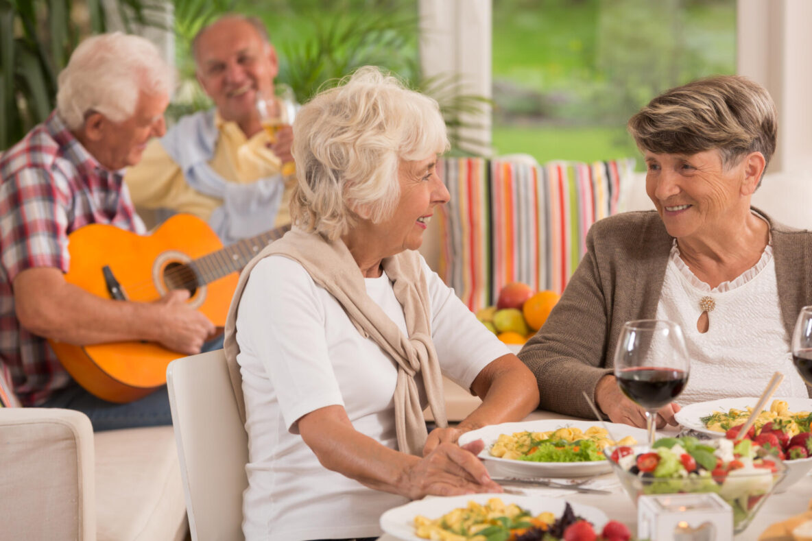 Two,Senior,Women,Talking,And,Drinking,Wine,,In,The,Background