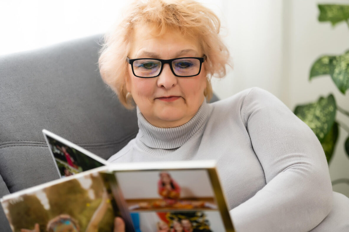 Women watching family album at home, elderly woman watching photobook