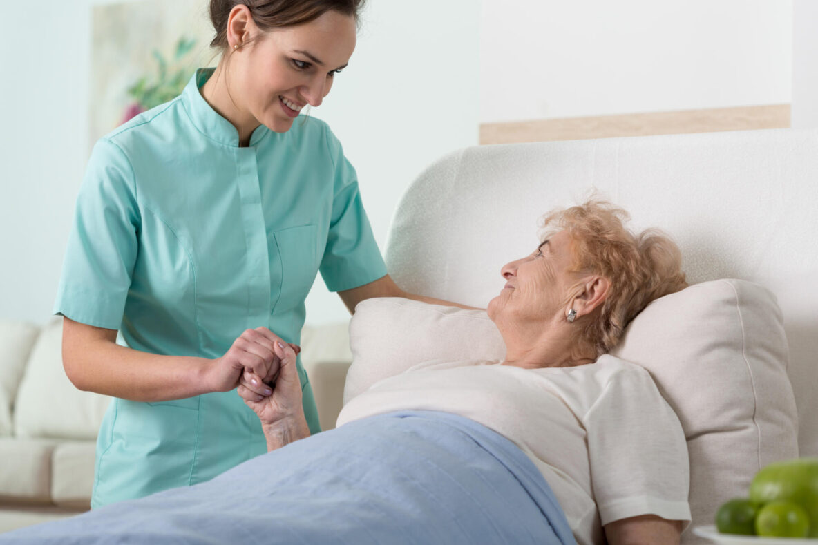 Senior,Woman,In,Hospital,Bed,Holding,Nurse's,Hand