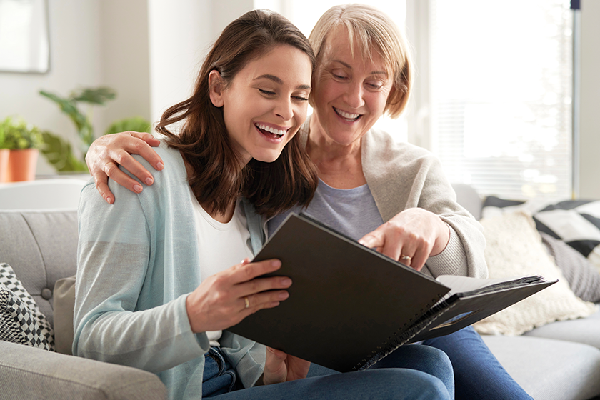 happy mother adult daughter looking photo album