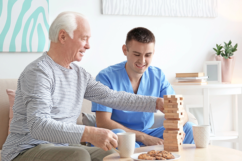 senior man playing board game with his caregiver