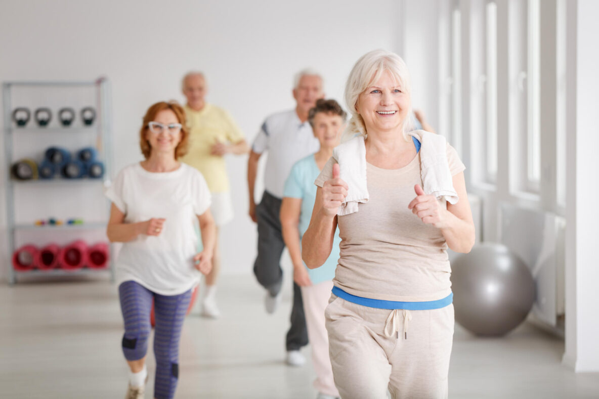 Happy,Active,Seniors,Exercising,Together,In,White,Spacious,Room