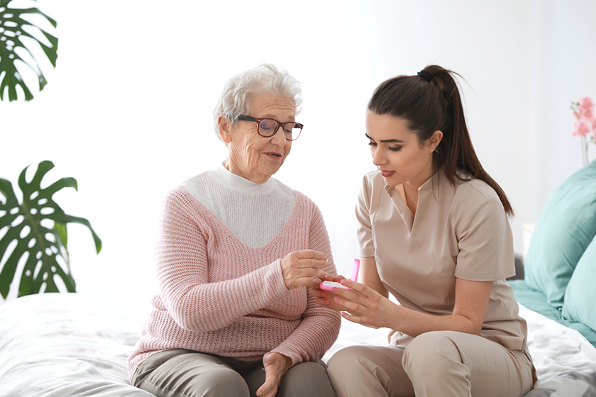 caregiver giving medicine to senior woman